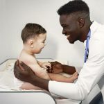 African doctor examines a little boy on couch