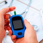 hand-holding-a-blood-glucose-meter-measuring-blood-sugar-the-background-is-a-stethoscope-and-chart-file