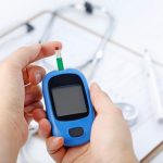 hand-holding-a-blood-glucose-meter-measuring-blood-sugar-the-background-is-a-stethoscope-and-chart-file